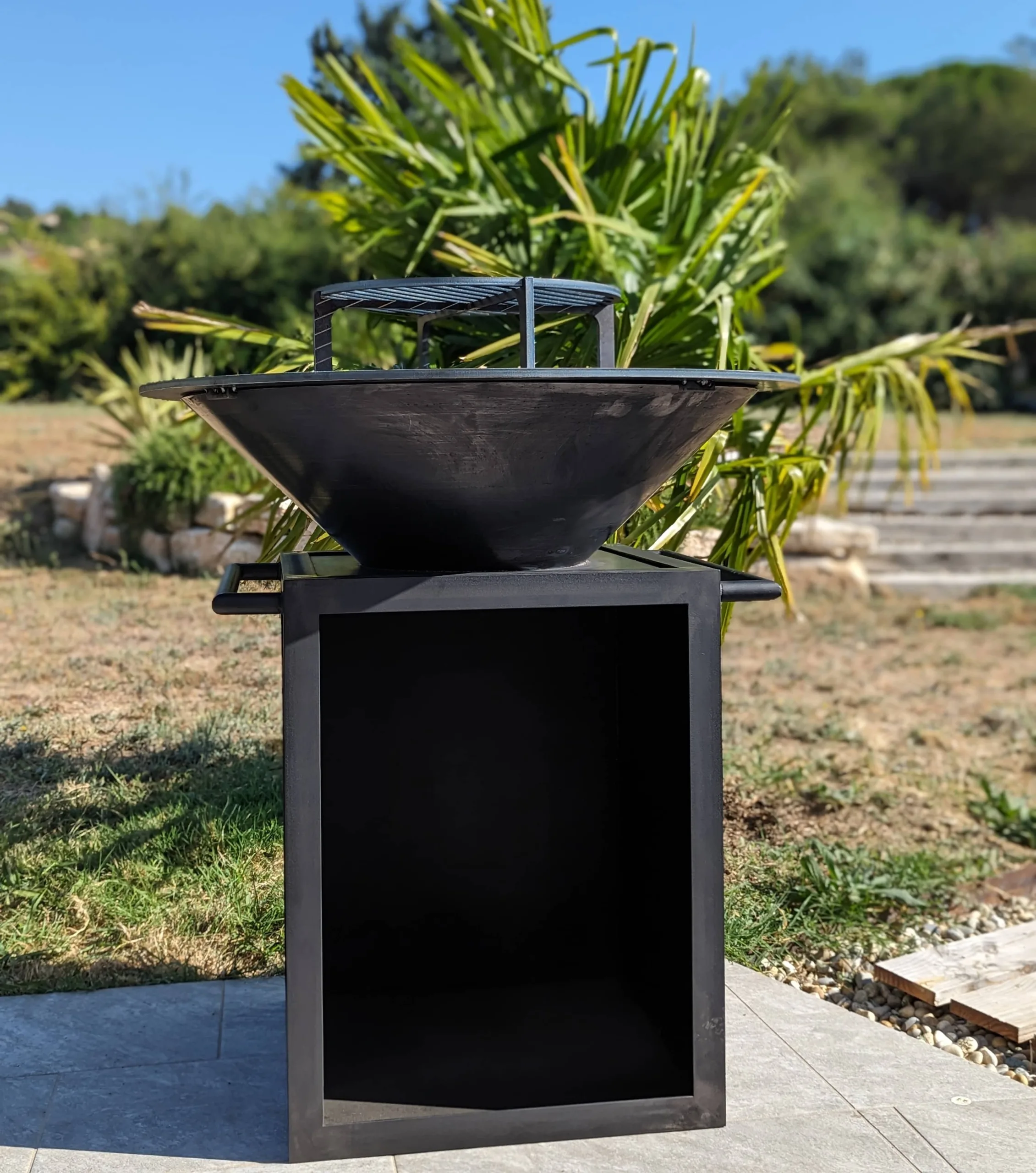 poignée-rangement-brasero-acier-terrasse brasero en acier avec poignées et rangement pour le bois sur une terrasse de jardin
